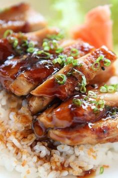 chicken with sauce and green onions on top of rice