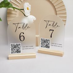 two table numbers are placed next to each other with a flower in the middle and one has a qr code on it