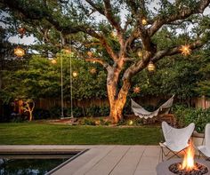 a backyard with a fire pit, hammock chairs and a tree in the background