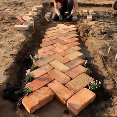 a man kneeling down next to a brick walkway made out of bricks on the ground