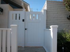 a white gate is next to a brick house