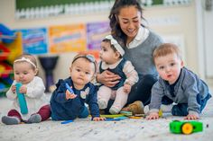 a woman sitting on the floor with four babies