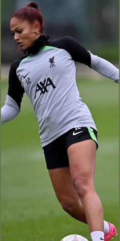 a woman kicking a soccer ball on top of a field