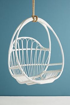 a white hanging egg chair in the shape of a bird cage on a blue background