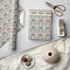 a table topped with wrapping paper next to scissors and other crafting supplies on top of a white surface