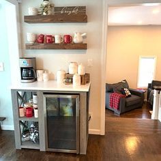 a kitchen area with a refrigerator, coffee maker and shelves on the wall above it