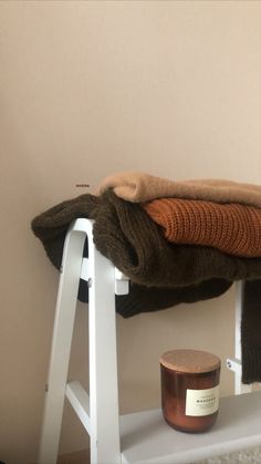 a white shelf with some blankets and a candle on it next to a brown wall