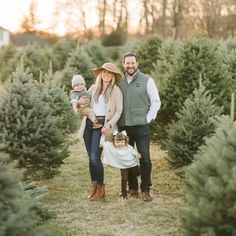 a man, woman and child are standing in the middle of a christmas tree farm