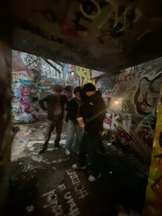 some people are standing in an alley with graffiti on the walls