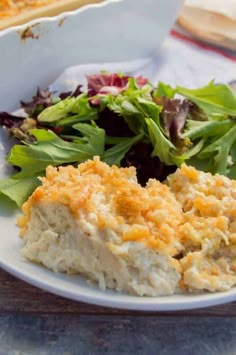 a white plate topped with food next to a salad