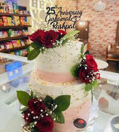 a three tiered cake with red roses and baby's breath on the top