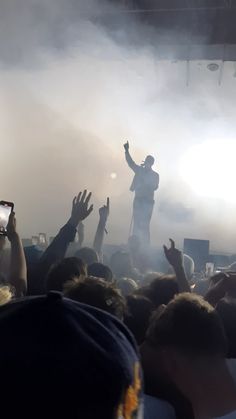 a man standing on top of a stage with his arms in the air and hands raised