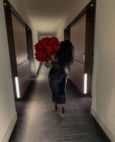 a woman walking down a hallway with red roses in her hair and heels on the floor