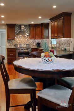 a kitchen with wooden floors and cabinets has a round dining table surrounded by four chairs