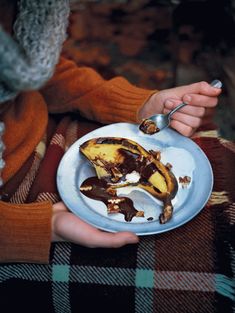 a person holding a plate with some food on it and spoon in their hand next to the plate