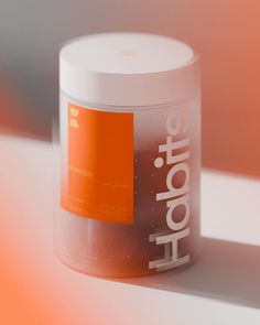 an orange and white container sitting on top of a table next to a pink wall