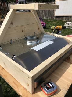 an open wooden box sitting on top of a picnic table next to a toolbox