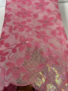 a pink lace with sequins on it sitting on top of a wooden table