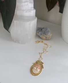 a gold necklace with a baby's head in the center on a white table