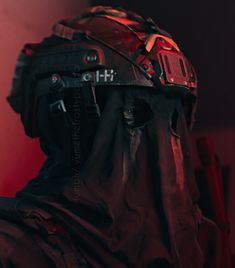 a man in a black mask and hood with a red light on his face is staring at something