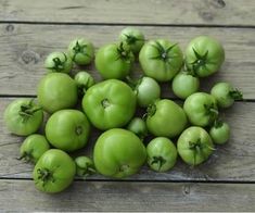 several green tomatoes on a wooden surface