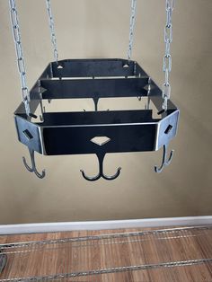 a metal shelf hanging from the ceiling with chains attached to it and two hooks on each side