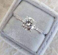 a diamond engagement ring sitting on top of a velvet box