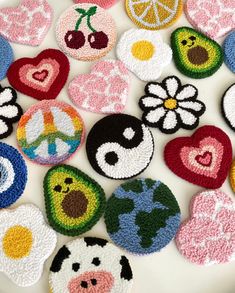 several crocheted patches are arranged on a white surface with fruit and flowers in the center