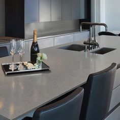 a bottle of champagne and two wine glasses on a kitchen counter