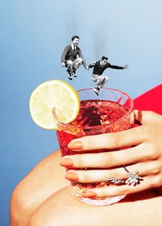 a woman holding a cocktail glass with lemon slices floating out of it