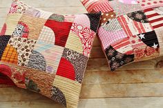 two decorative pillows are sitting on a wooden surface together, one is made with patchwork and the other has an american flag design