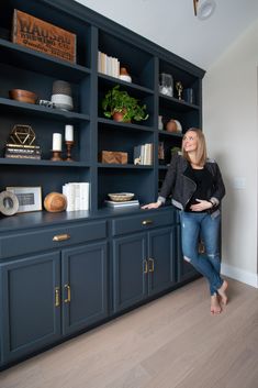 a woman standing in front of a blue bookcase