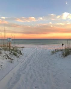 there is a person walking on the beach at sunset