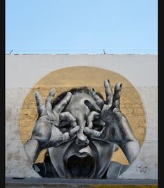 a large mural on the side of a building with hands covering it's face