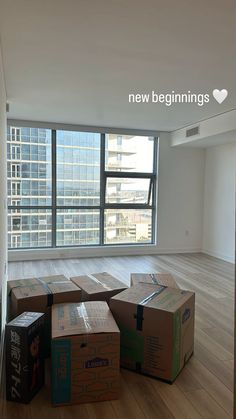 several boxes are stacked on the floor in an empty room with large windows and wooden floors