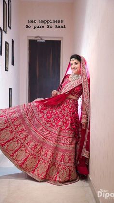 a woman in a red and gold bridal gown posing for the camera with her hand on her hip