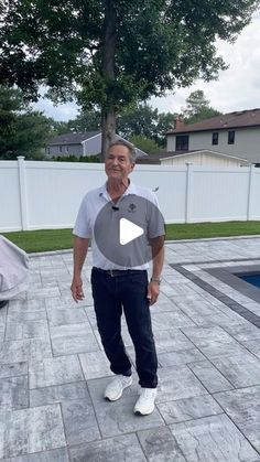 a man standing in front of a swimming pool with his hands in his pockets and looking at the camera