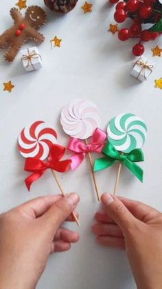 two hands holding lollipops with bows on them