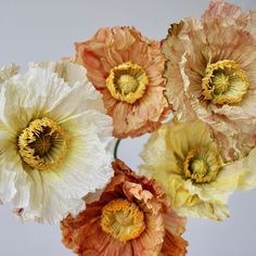 four different colored flowers are in a vase