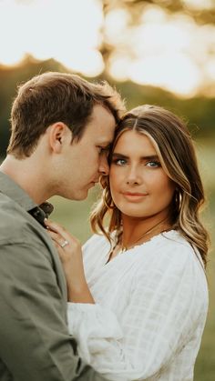 a man and woman standing next to each other in front of the sun with their faces close together