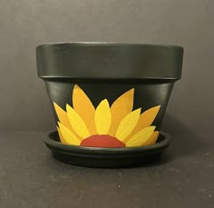 a black pot with a yellow flower painted on it