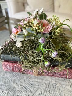 an arrangement of flowers sitting on top of two books