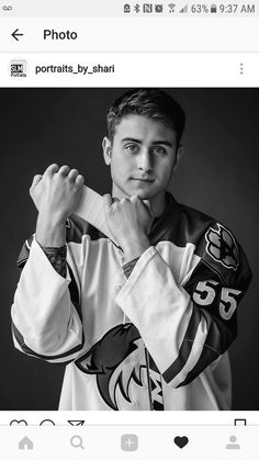 a black and white photo of a young man wearing a hockey jersey with his hands on his chest