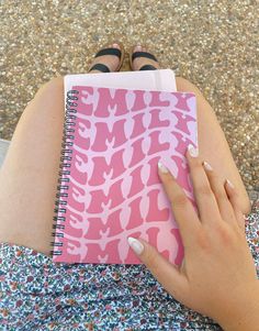 a woman's hand is holding a pink notebook