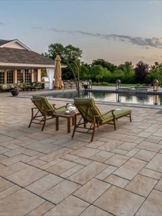 two lawn chairs sitting on top of a patio next to a swimming pool