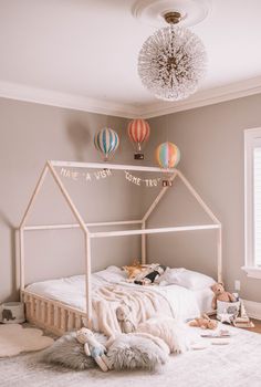 a child's bedroom with hot air balloons hanging from the ceiling and toys on the floor