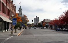 an empty street with cars parked on both sides and buildings in the backround