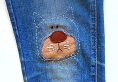 a close up of a pair of blue jeans with a cat face on the back