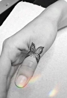 a woman's hand with a butterfly tattoo on the left side of her finger