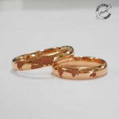 two gold wedding rings sitting next to each other